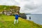 Happy Mexican mature woman on the Cliffs of Moher with the Branaunmore sea stack in the background