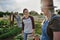 Happy mid adult female farmer with her senior friend carrying crate with homegrown vegetables outdoors at community farm