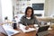 Happy middle aged African American  woman sitting at table in her dining room making notes, selective focus