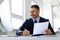 Happy middle aged businessman working with computer and documents in office, male entrepreneur in suit sitting at desk