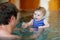 Happy middle-aged father swimming with cute adorable baby daughter in whirl pool. Smiling dad and little child, girl of