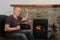 Happy middle aged man sitting near a hot burning fireplace, winter relaxation concept