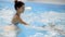 Happy middle-aged mother swimming with cute adorable baby in swimming pool. Smiling mom and little child, newborn girl