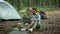 Happy middle aged spouses resting at camping and web surfing online on laptop, bonding near tent, free space