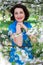 Happy middle aged woman with blooming cherry tree in garden