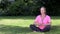 Happy middle aged woman in her forties outside cross legged practicing yoga in prayer or lotus position