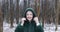 Happy middle aged woman in winter forest. Adult woman with headband wear hood of green jacket from eco fur.