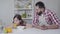 Happy Middle Eastern father in apron giving orange juice to cute daughter eating cereals in the morning. Young man