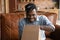 Happy millennial Afro American hipster guy unpacking parcel at home