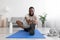 Happy millennial black bearded sportsman make exercise for legs, stretching on floor on mat with dumbbells