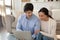 Happy millennial couple sitting on floor relaxing by laptop screen