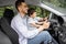 Happy millennial dad teaching little boy with steering wheel to drive car in summer, outdoor, profile