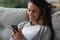 Happy millennial girl relax on couch using cellphone