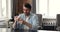 Happy millennial male sitting at table using modern mobile phone