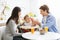 Happy millennial parents feeding baby boy at kitchen