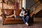 Happy millennial spouses rest on couch at wooden cottage interior