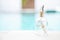 Happy miniature couple on glass message bottle over blurred blue swimming pool water background