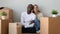 Happy mixed ethnicity couple looking at camera sit with boxes