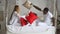 Happy mixed ethnicity family mom, african dad and little kid daughter having fun red pillow fight on bed. Young multi