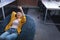 Happy mixed race businesswoman chilling in office relaxing space lying in beanbag using smartphone