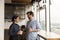 Happy mixed race couple drink tea coffee by picture window