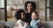 Happy mixed race family mother hugging diverse daughters at home