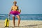 Happy mixed race hispanic brazil woman in yellow swimming suit bra and demin shorts having fun at beach with ribbon