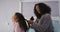 Happy mixed race mother and daughter brushing hair in bedroom