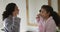 Happy mixed race mother and daughter brushing teeth in bathroom