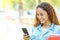 Happy mixed race student checking phone in a park