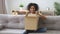 Happy mixed race woman sitting on couch opens received parcel