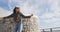 Happy mixed race woman skateboarding with arms in the air and smiling on sunny promenade by the sea