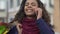 Happy mixed-race woman talking on smartphone and holding colorful shopping bags