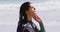 Happy mixed race woman in wetsuit standing on beach looking out to sea