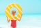 Happy modern child with yellow inflatable lifebuoy on seashore