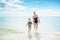 Happy modern mother and child on beach coming out of sea