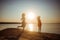 Happy mom and daughter in dresses are jumping and dancing on the beach during sunset. Good relations of two generations. Health