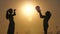 Happy mom and daughter, family resting in the park with a volleyball ball at sunset. Silhouette of children playing ball