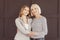 Happy mom and daughter looking at camera over brown wall