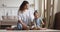 Happy mom with kid daughter playing dinosaurs sit on floor