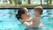 Happy mom is swimming in the pool with her little son, she kisses the baby.
