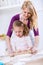 Happy Mom teaches daughter how to use a rolling pin