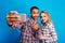 Happy moments together of excited lovely couple having fun on blue background. Making selfie portrait, cheerful mood