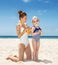 Happy mother applying sunscreen on girl in swimsuit at beach