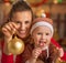 Happy mother and baby showing christmas ball