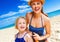 Happy mother and child on seashore applying suntan lotion