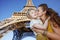 Happy mother and child tourists kissing against Eiffel tower