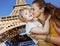 Happy mother and child tourists kissing against Eiffel tower