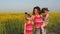 A happy mother with children is photographed in nature. The family makes self in nature. Woman with children in a field of yellow