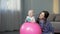Happy mother and cute baby girl smiling at camera, playing with balls at home